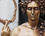 Bronzestatue der Aphrodite, die einen verzierten Spiegel hält. Ihr lockiges Haar und ihr sanfter Blick unterstreichen ihr klassisches Aphrodite-Aussehen.