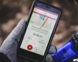 Rękawiczka trzyma smartfon z aplikacją licznik rowerowy. Widoczny czas 00:04:11, dystans 0,4 km i średnia prędkość 6,4 km/h.