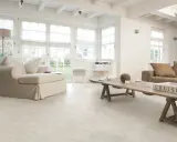Luminoso soggiorno con divani chiari, tavolino in legno grezzo e un elegante soggiorno con pavimento bianco.