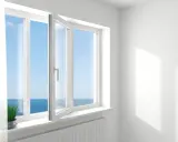 Ventanas oscilobatientes con vista al mar. Una planta verde decora el alféizar.