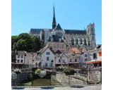 Blick auf malerische Häuser und die Kathedrale in Amiens, Frankreich. Blumenkästen schmücken eine Brücke über einen Kanal.