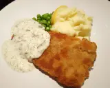 En gyllene panerad fisk med krämig sås, len potatismos, gröna ärtor och en citronklyfta. En klassisk och god måltid.