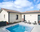 Vue aérienne d'une maison moderne avec piscine, le **plan maison en L** est bien visible, entouré de verdure.