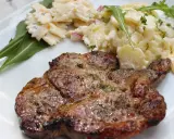 Saftiges Nackensteak grillen mit Kartoffel- und Nudelsalat auf einem weißen Teller.