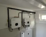 Två Growatt-växelriktare och en batteribank för solceller monterade på en vägg. Kablar dras snyggt längs väggen.