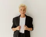 Elegancka kobieta z blond włosami, w czarnej marynarce w paski, pokazuje, jak powinna leżeć marynarka, podkreślając jej stylowy krój.