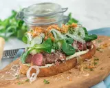En saftig steak sandwich med möra skivor av biff, krämig majonnäs, färska gröna blad, krispig lök och riven parmesanost på rostat bröd.