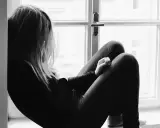 Una joven sentada en la ventana, con la mirada perdida. Un momento para reflexionar sobre qué decirle a tu hija cuando le rompen el corazón.