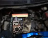Zardzewiały zawór EGR w dłoni mechanika, gotowy do montażu w silniku.