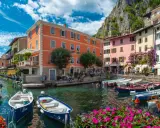 Colorate case sul lungolago di Limone sul Garda, con barche ormeggiate e fiori vivaci. Un luogo incantevole da scoprire, perfetto per capire cosa visitare a Limone sul Garda.