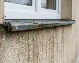 Zacieki na elewacji po deszczu, brudny parapet pod oknem.