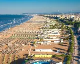 La riviera romagnola dove andare: una distesa infinita di ombrelloni e lettini sulla sabbia dorata, con il mare azzurro e la città sullo sfondo.
