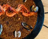 Paella de marisco recién hecha, con gambas rojas, mejillones y almejas sobre arroz dorado.