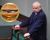 Polityk w garniturze pochyla się nad mównicą, obok widoczny Big Mac. Zastanawia się nad big mac cena?