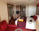 Cabina MSC Musica con letto, divano rosso, specchio e TV. Perfetta per una vacanza in crociera.