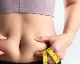 Frau kneift Bauchfett, Maßband zeigt Umfang. Tipps für 10 Hausmittel gegen Bauchfett.