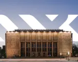 Monumentalna fasada Muzeum Narodowego w Krakowie przy Alei 3 Maja, oświetlona wieczorem.
