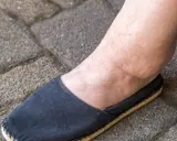 Spuchnięta kostka i stopa w czarnym bucie, objaw problemów z nerkami.