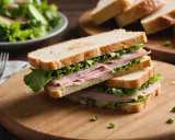 Un délicieux sandwich pain viennois garni de jambon et de laitue fraîche, prêt à être dégusté.