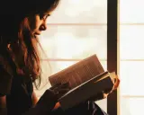 Ragazza immersa nella lettura, illuminata dalla luce dorata del tramonto, sfoglia pagine che potrebbero contenere i libri di Emmanuel Carrère.