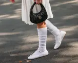 Piernas con bailarinas blancas y calcetines blancos arrugados, un look chic para bailarinas con calcetines.