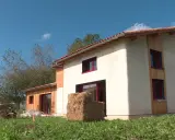 Maison écologique en paille, un projet de prix maison en paille clé en main. Le bâtiment est en cours de finition, avec des murs enduits et des accents de bois.