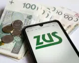 Pieniądze i telefon z logo ZUS. Sprawdź, ile płatne jest opieka nad chorym członkiem rodziny.
