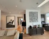 Guy Hepner stands in a modern apartment filled with art, including a large black and white drawing and a textured sculpture.