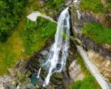 Majestätischer norwegischer Wasserfall stürzt in ein türkisfarbenes Becken. Wege führen Besucher nah heran.