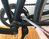 Montaż stopki rowerowej. Klucz dokręca śrubę mocującą stopkę do ramy roweru.
