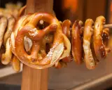 Des bretzels dorés, saupoudrés de gros sel, sont suspendus sur un support en bois. Ces spécialités lorraines invitent à la dégustation.