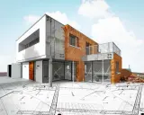 Nowoczesny dom w budowie, z cegły i betonu, na tle planów architektonicznych. Od czego zacząć budowę domu? Od projektu!