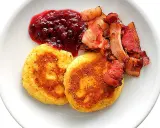 Två gyllene potatisbullar med lingonsylt och knaperstekt bacon. Ett klassiskt recept på potatisbullar som passar perfekt till frukost eller middag.