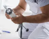 Un bricoleur prépare son pistolet à mastic pour une application. Il tient le tube de mastic Sika, prêt à l'emploi.