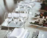 Trois verres à eau sont disposés sur une table dressée, prêts pour un repas.