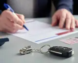Kluczyki do auta i breloczek w kształcie samochodu leżą obok dokumentów. Może to oznaczać niezapłaconą ratę OC przez sprzedającego.