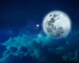 Pełnia księżyca w Byku, otoczona gwieździstym niebem i ciemnymi chmurami, tworzy magiczny widok.