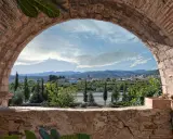 Vista de un pueblo desde un arco de ladrillo. Un paisaje con montañas y vegetación, ideal para ver en altura.