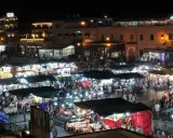 Belebter Marktplatz in Marokko bei Nacht. Viele Stände mit Lichtern und Menschen, die einkaufen und essen. Wann ist Ramadan in Marokko?