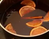 Une marmite remplie d'un liquide sombre, avec des tranches d'orange, un bâton de cannelle et de l'anis étoilé. Parfait pour une recette punch simple et réconfortante.