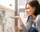 Donna preoccupata osserva muffa su muro, cercando soluzioni su come eliminare umidità in casa.