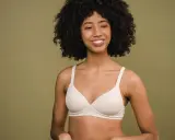 Donna sorridente con un reggiseno color carne. Un reggiseno troppo stretto conseguenze possono essere scomode, ma questo sembra comodo.