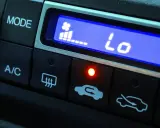 El aire acondicionado del coche muestra "Lo" indicando baja temperatura. El ventilador está al mínimo y la luz roja está encendida.