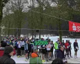 Läufer warten am Start-Ziel-Bogen für einen ultra marathon. Eine digitale Uhr zeigt 9:59:55.