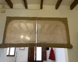 Dos estores enrollables caseros de tela de yute cubren una ventana y una puerta.