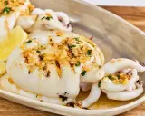 Delicioso sepia a la plancha con ajo, perejil y limón, servido en una bandeja.