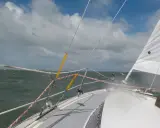 Vue depuis un voilier, mer agitée sous un ciel nuageux. Le gréement et la voile blanche sont visibles. Fiche technique du Challenger Scout.