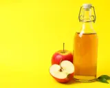 Bouteille de vinaigre de cidre et pommes rouges, un remède naturel pour l'urticaire.