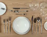 Une table dressée avec un **caractère élégant** : assiettes blanches, couverts en argent, verres à pied et une serviette décorée.