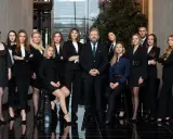 Grupa prawników i adwokatów w eleganckich strojach pozuje do zdjęcia w nowoczesnym wnętrzu.